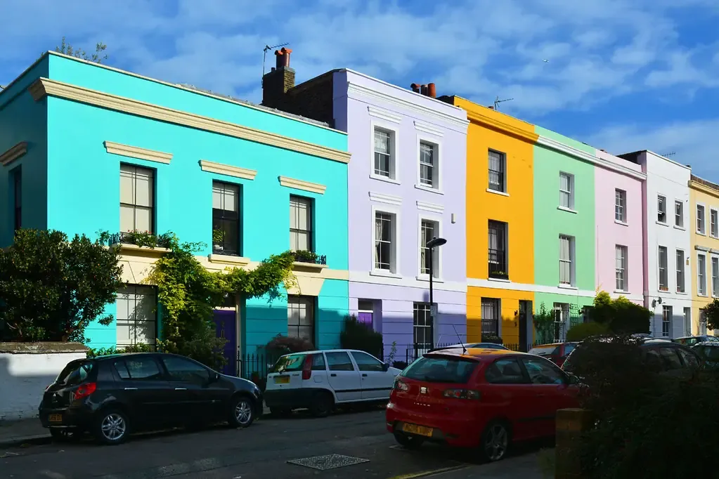 Row of colour-washed Victorian terrace houses on Falkland Road in Kentish Town under a blue sky