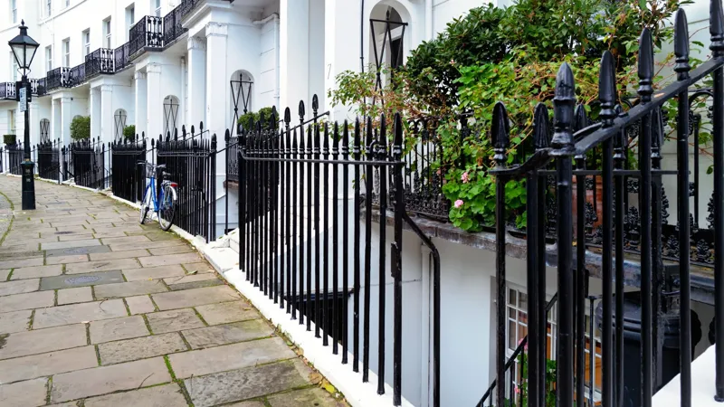 Cream-painted Georgian townhouses in Kensington with black railings around lightwells at pavement level