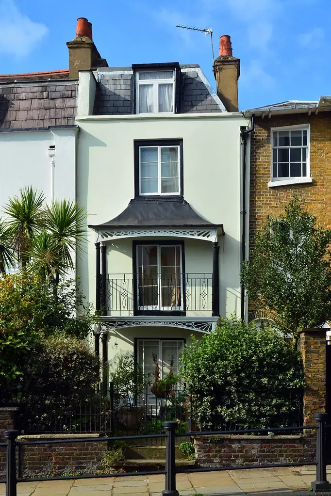 Narrow period house on Heath Street in Hampstead with a bay window and pale green render