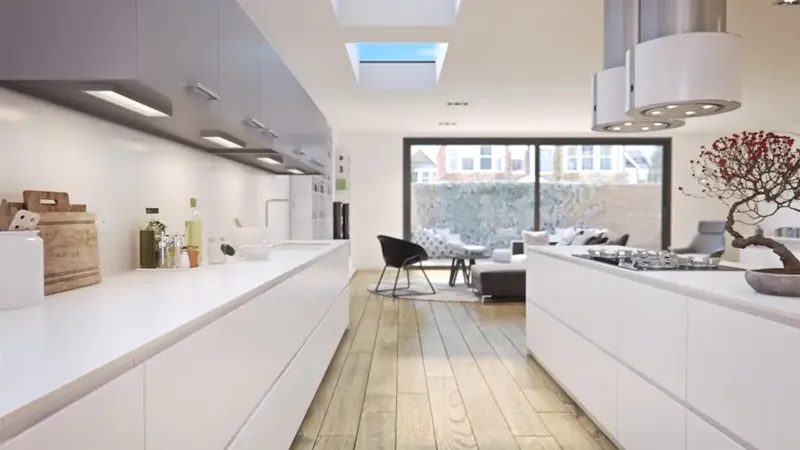 A bright white kitchen with a rooflight above and glazed doors to the garden
