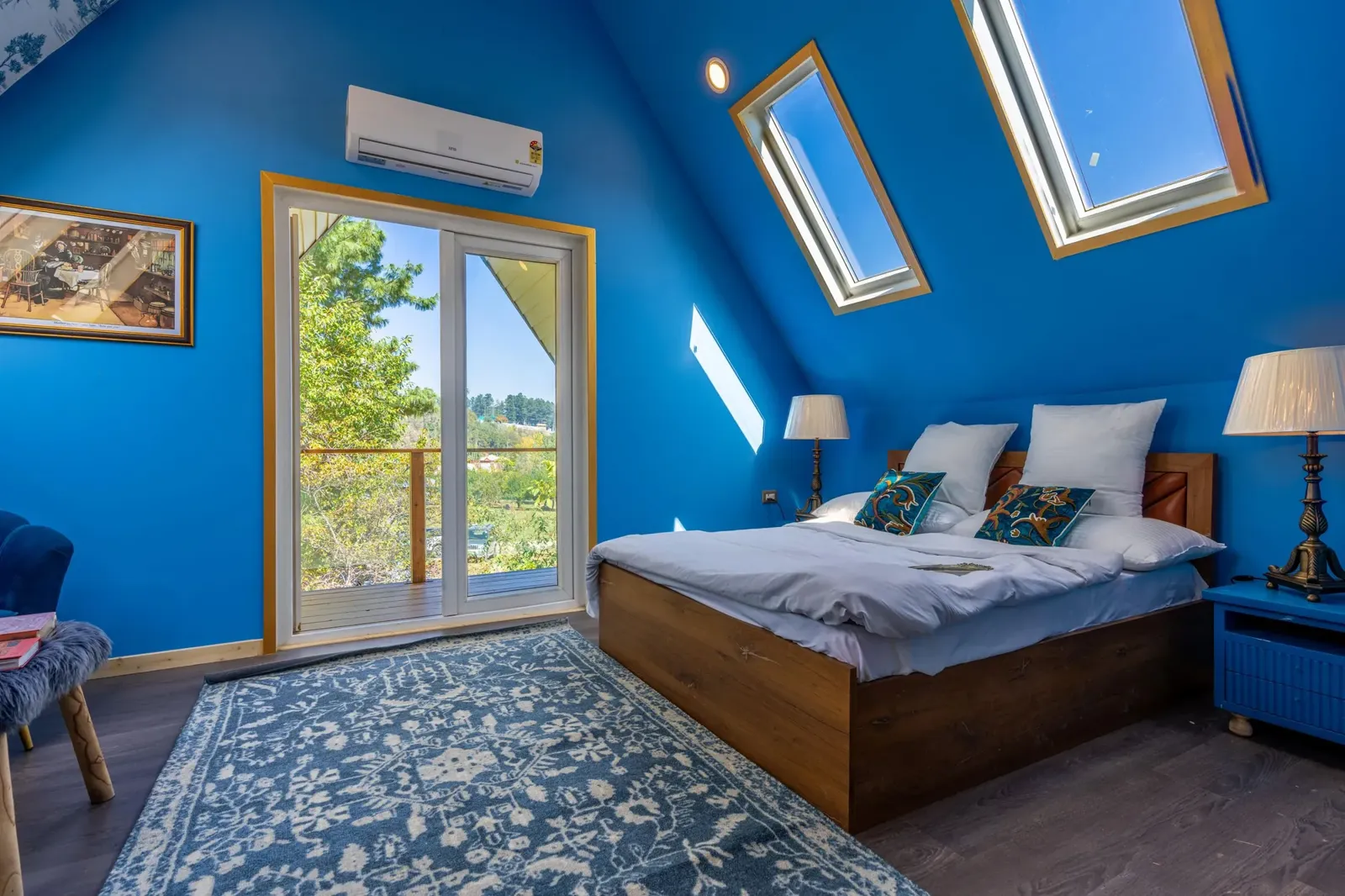 Loft bedroom with a pitched ceiling, two roof windows and glazed doors opening onto a small balcony