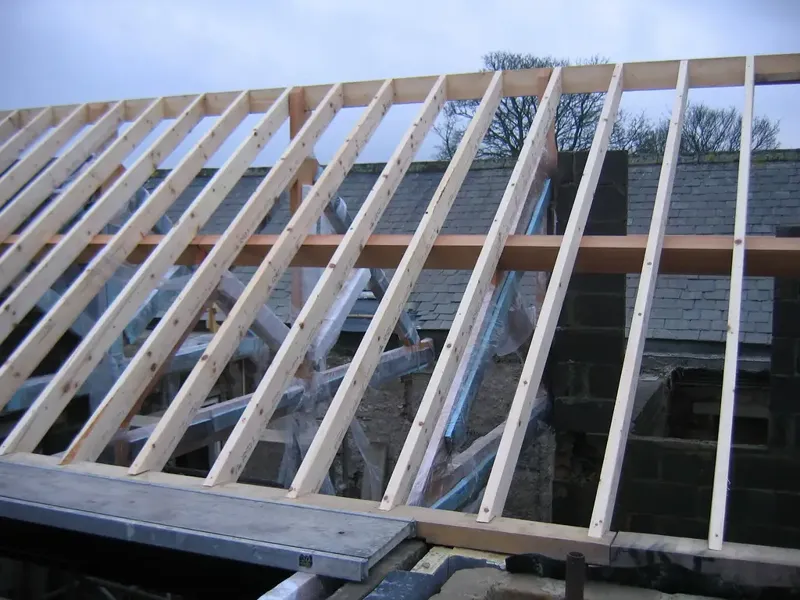 New timber roof rafters set out over a masonry wall during a house renovation