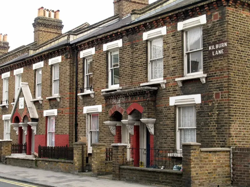 Terrace of yellow-brick Victorian cottages with white sash windows and red door surrounds on a London street