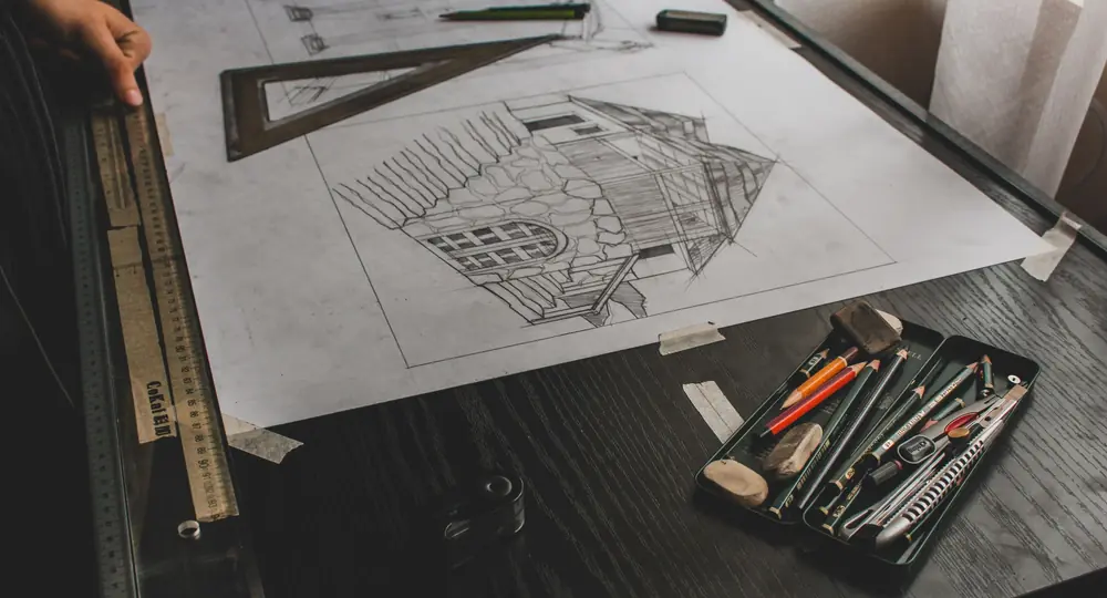 Architectural elevation sketch on a drafting board with set square, rulers and pencils on a dark desk