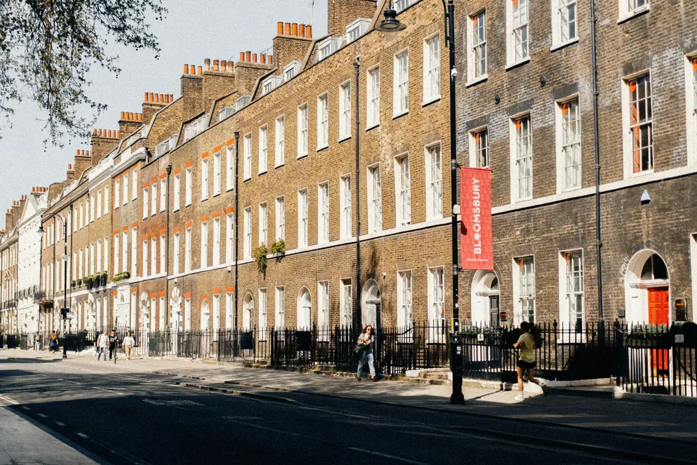 Long terrace of Georgian brick townhouses with chimney stacks, fanlights and black railings in Bloomsbury