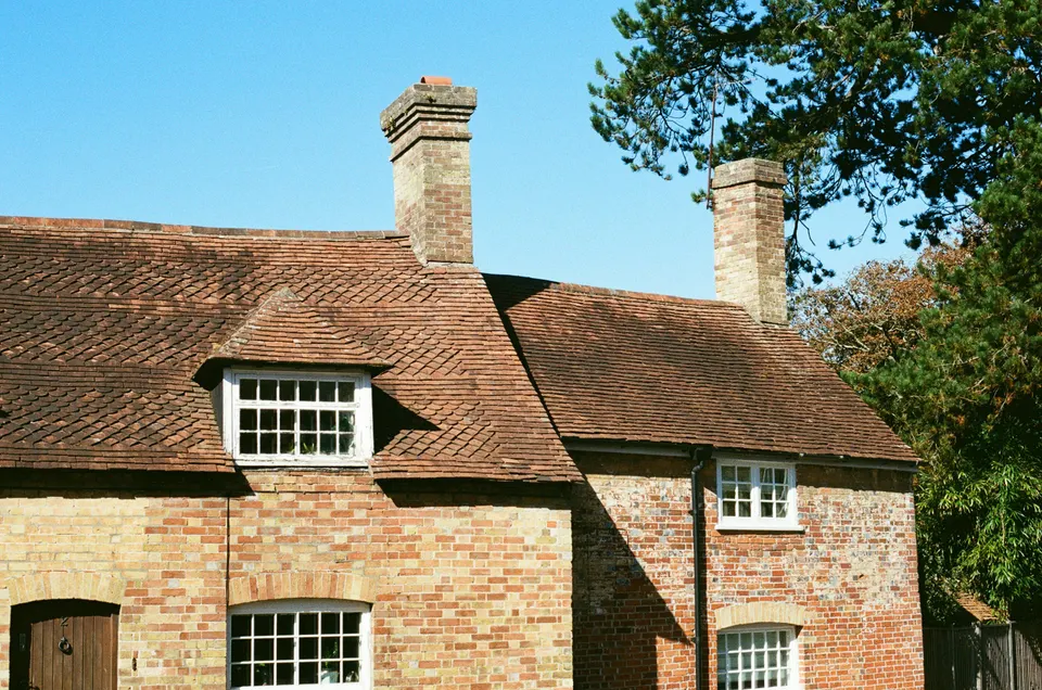 Brick cottage with a tiled roof, chimneys and a front dormer window