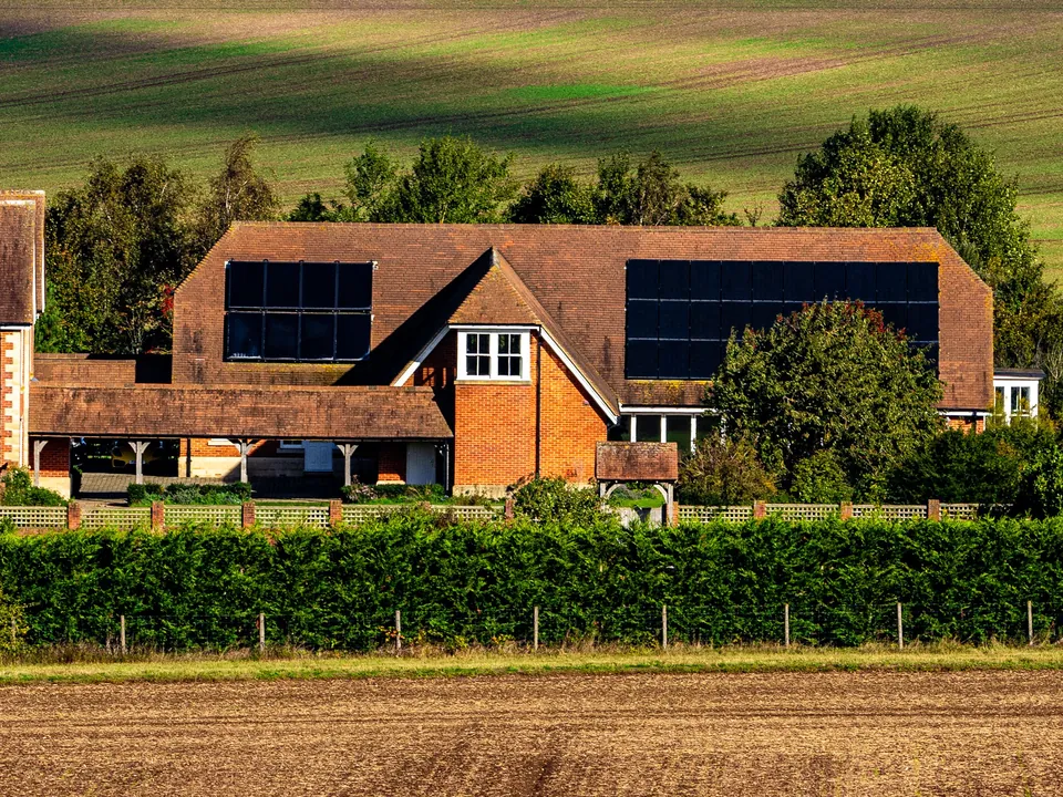 Red-brick English house with rows of solar panels on its tiled roof